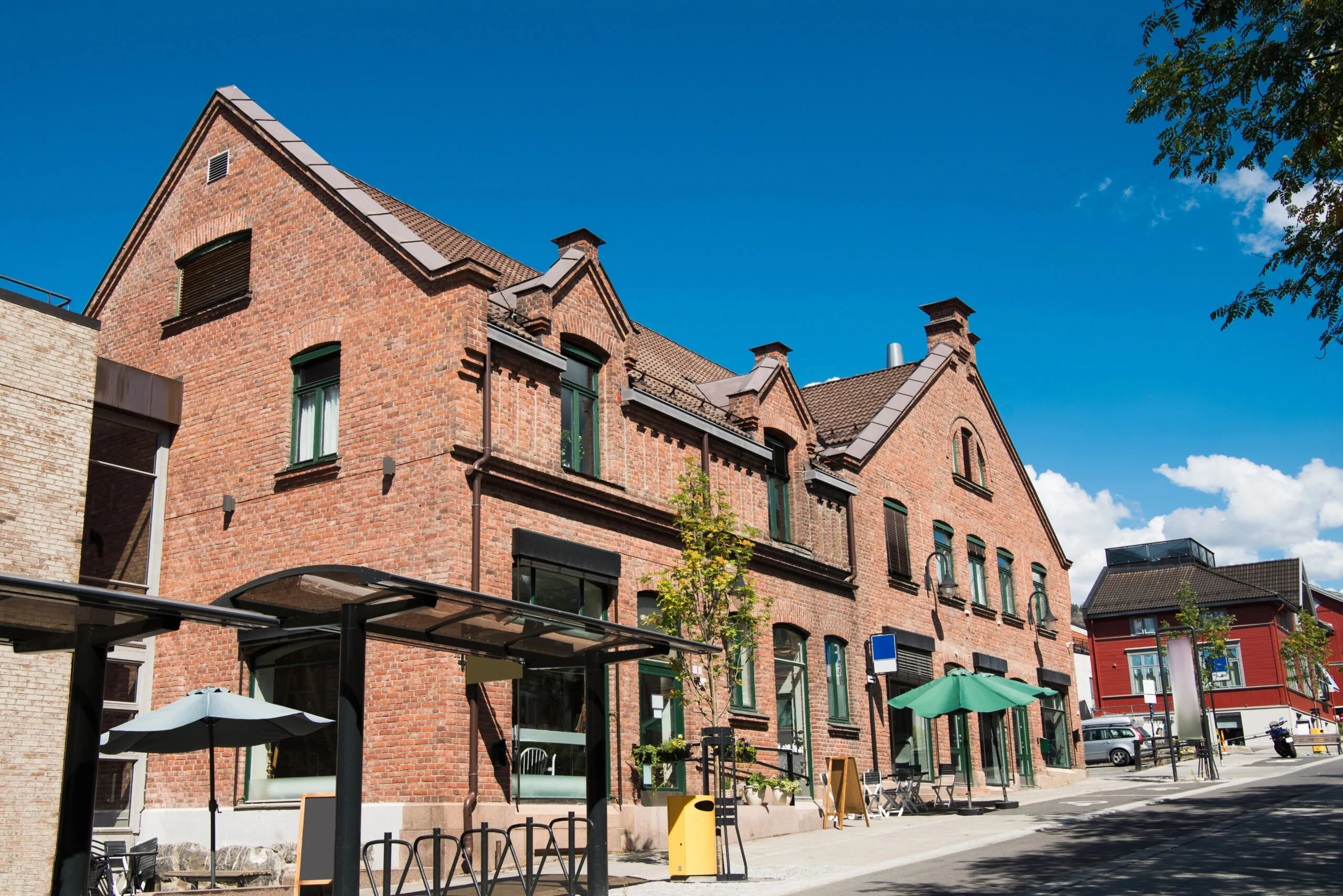 a brick building with umbrellas and a bus stop